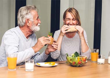 Older couple with dental implants in Granby enjoying a meal