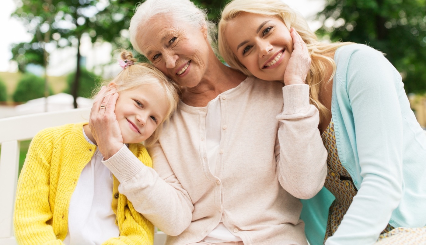 Three generations of women smiling outdoors