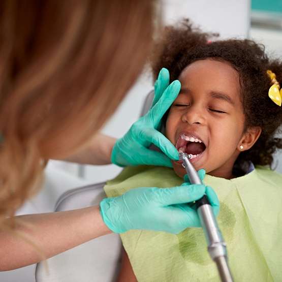 Young girl in dental chair having her teeth cleaned