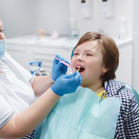 Child in dental chair having fluoride applied to their teeth