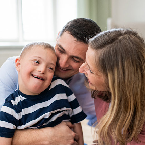 Mother and father hugging their young son with Down syndrome