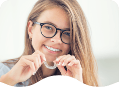 Smiling young woman holding Invisalign aligner