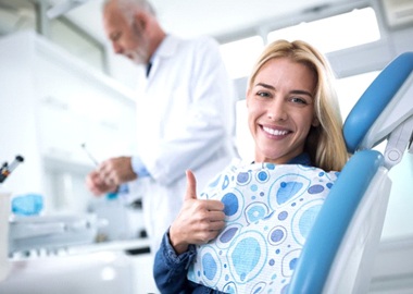 woman giving thumbs up in dental chair  