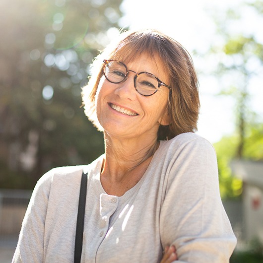 Senior woman with glasses walking outside smiling