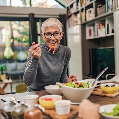 Senior woman sitting at table eating a salad