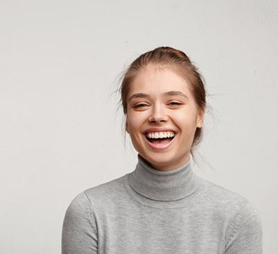 smiling woman holding an Invisalign aligner 