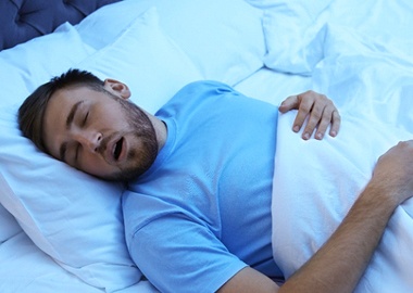 Young man with sleep apnea, in bed snoring