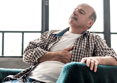 Senior man sitting in chair, suffering from poor health
