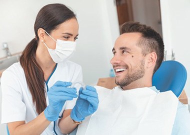 Dental assistant smiling at patient while holding teeth whitening tray