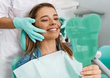 a woman checking her smile after undergoing teeth whitening