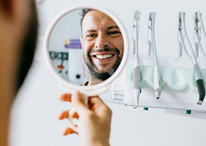a man checking his smile with a mirror
