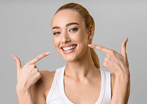 a woman pointing at her bright and healthy teeth