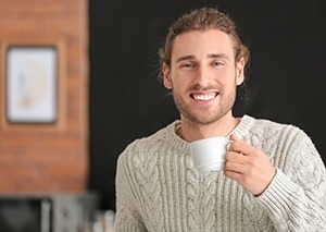 a man smiling with bright teeth while holding a cup