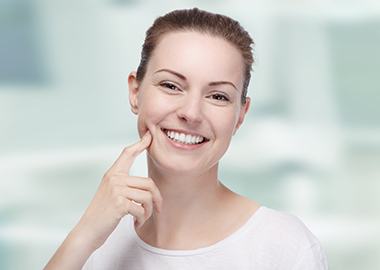 Smiling female dental patient tapping her cheek