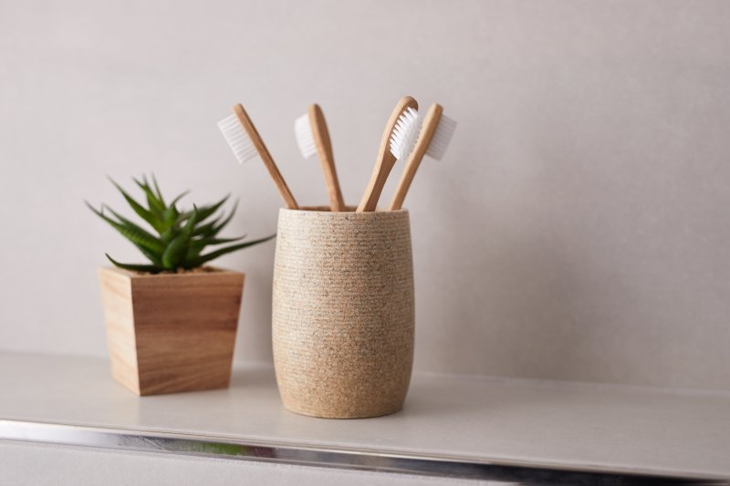 Bamboo toothbrushes sitting in cup on shelf