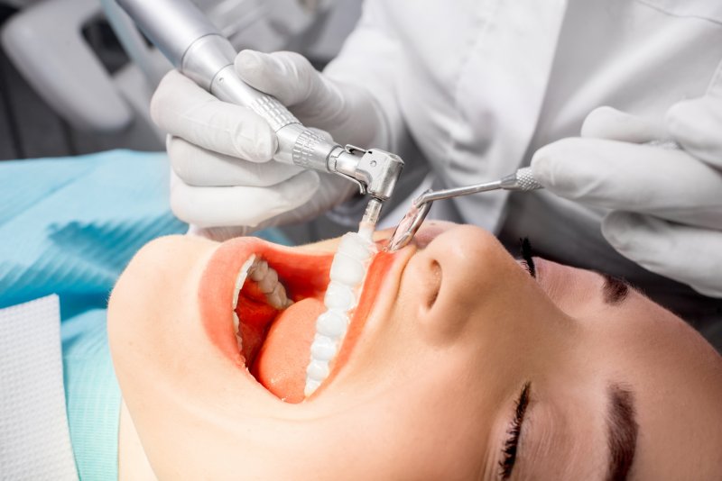 an up-close view of a dentist performing a cleaning on a female patient’s smile