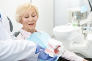 older woman talking to dentist about slipping dentures