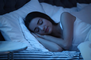Young woman sleeping peacefully in bed at night