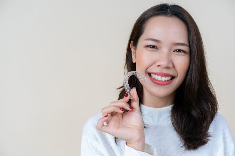 Woman smiling and holding dental aligner.