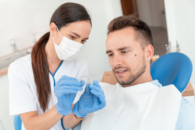 Dentist shows an Invisalign tray to a patient.