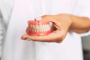 Dentist with white coat holding dentures